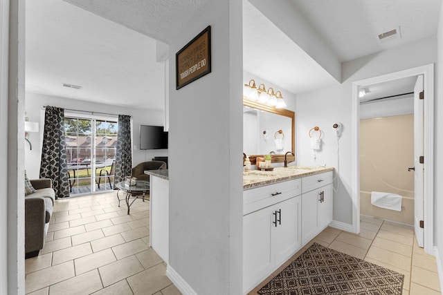 bathroom featuring tile patterned flooring, vanity, and a textured ceiling