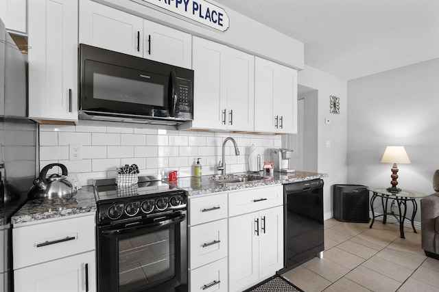 kitchen with light tile patterned flooring, sink, white cabinetry, and black appliances