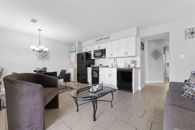 kitchen with decorative light fixtures, backsplash, white cabinetry, black appliances, and a notable chandelier