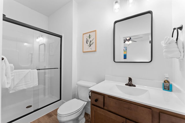 bathroom with ceiling fan, toilet, a shower with shower door, hardwood / wood-style flooring, and vanity