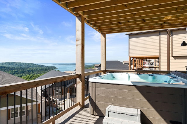 wooden deck featuring a water view and a hot tub