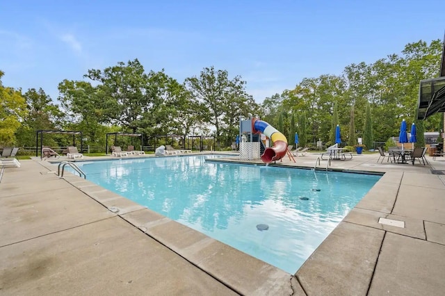 view of pool with a water slide and a patio