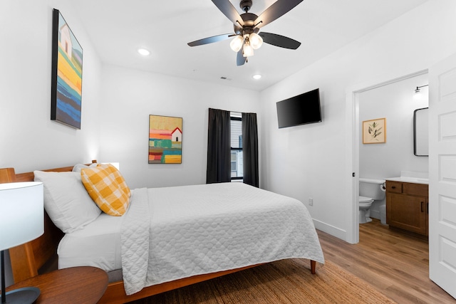 bedroom with ceiling fan, light wood-type flooring, and ensuite bath