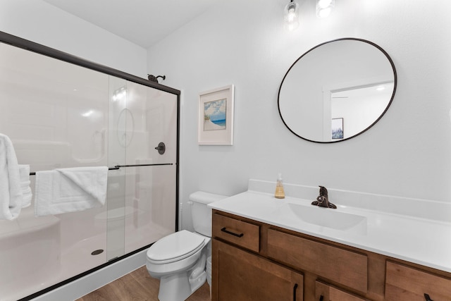 bathroom with hardwood / wood-style flooring, vanity, toilet, and a shower with shower door