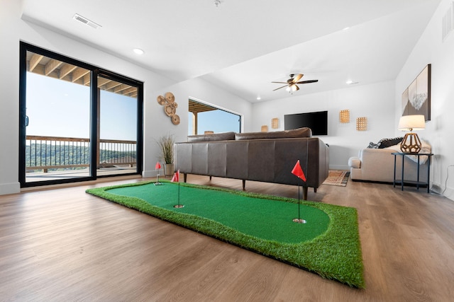 recreation room featuring golf simulator, hardwood / wood-style floors, and ceiling fan