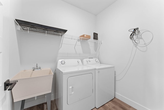 laundry area featuring separate washer and dryer, sink, and light hardwood / wood-style flooring