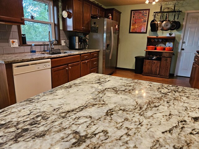 kitchen featuring sink, white dishwasher, backsplash, and stainless steel fridge