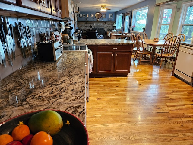 kitchen with stove, white dishwasher, stone counters, light hardwood / wood-style floors, and ceiling fan