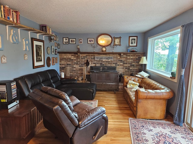 living room with a fireplace, light hardwood / wood-style floors, and a textured ceiling