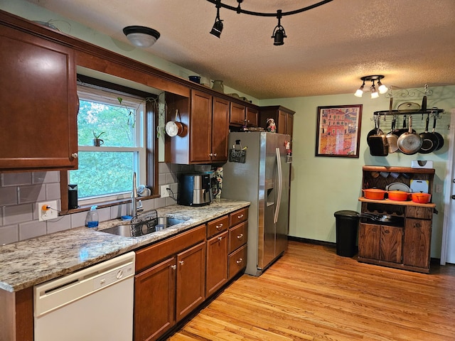 kitchen with dishwasher, stainless steel refrigerator with ice dispenser, light hardwood / wood-style flooring, and backsplash