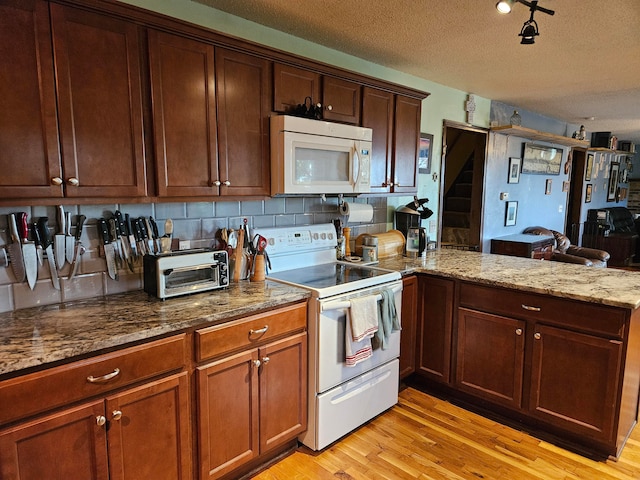 kitchen featuring a textured ceiling, white appliances, light stone countertops, kitchen peninsula, and light hardwood / wood-style flooring