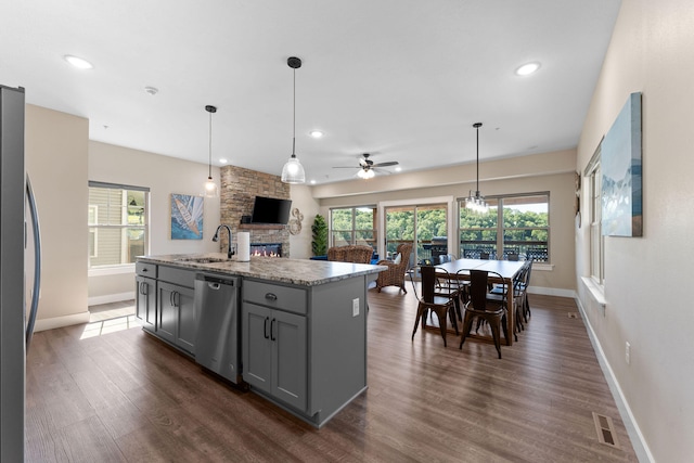 kitchen featuring appliances with stainless steel finishes, gray cabinetry, a kitchen island with sink, and dark wood-type flooring