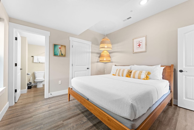 bedroom featuring ensuite bathroom and hardwood / wood-style floors