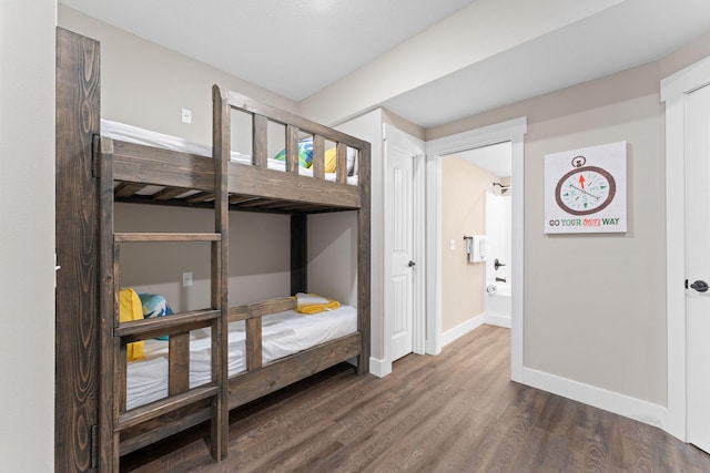 bedroom featuring ensuite bath and dark wood-type flooring