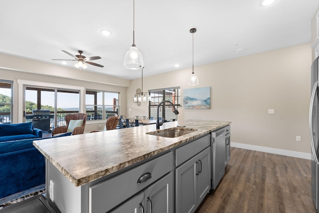 kitchen featuring an island with sink, sink, decorative light fixtures, dishwasher, and dark hardwood / wood-style flooring