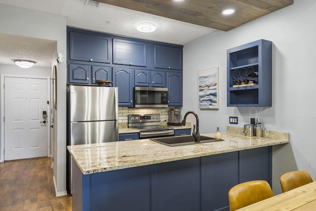 kitchen featuring stainless steel appliances, blue cabinetry, sink, kitchen peninsula, and a kitchen breakfast bar