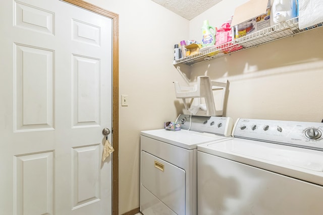 laundry area featuring washing machine and clothes dryer and a textured ceiling