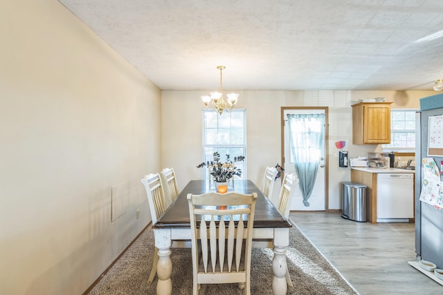 dining room featuring a notable chandelier, a textured ceiling, and light wood-type flooring