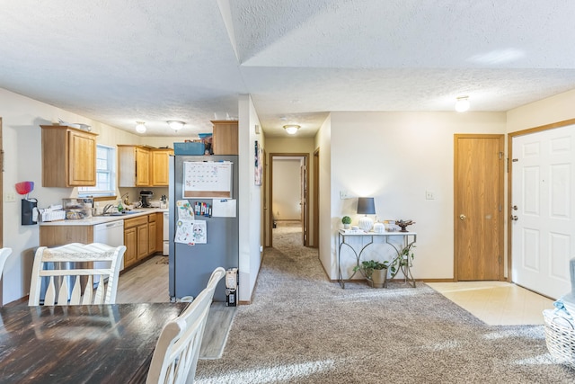 kitchen with sink, light carpet, a textured ceiling, and stainless steel refrigerator