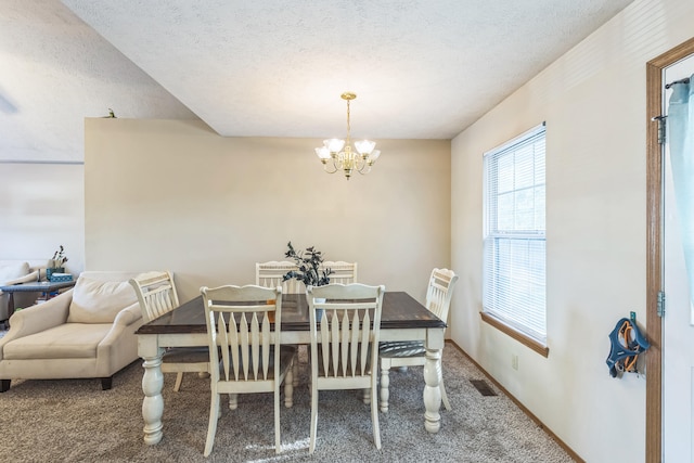 dining space featuring carpet floors, a chandelier, and a textured ceiling