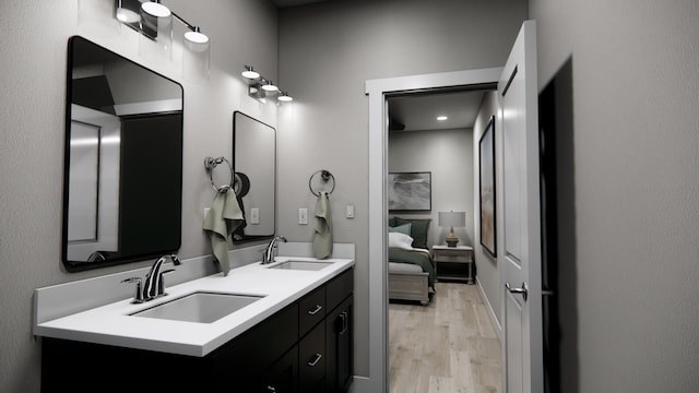 full bath featuring connected bathroom, wood finished floors, a sink, and double vanity