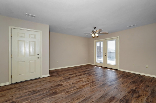 empty room with dark wood-type flooring, visible vents, ceiling fan, and french doors