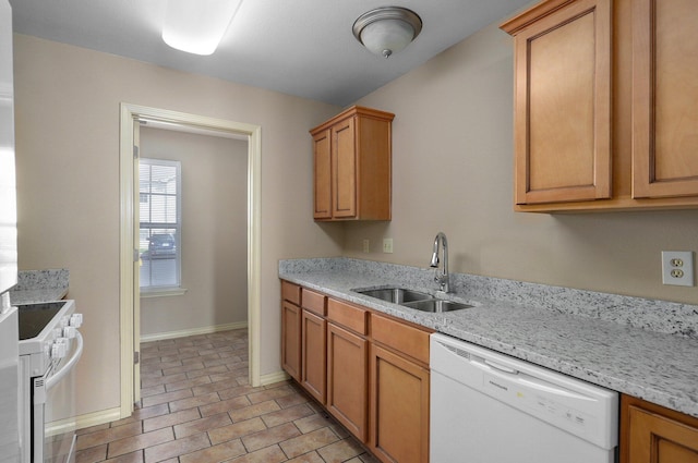 kitchen featuring light stone counters, baseboards, a sink, and white appliances