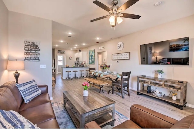 living room with light hardwood / wood-style flooring and ceiling fan