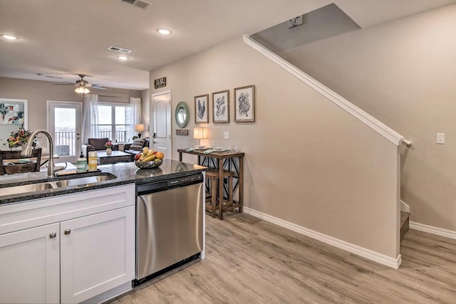 kitchen featuring stainless steel dishwasher, white cabinets, dark stone countertops, sink, and light hardwood / wood-style flooring