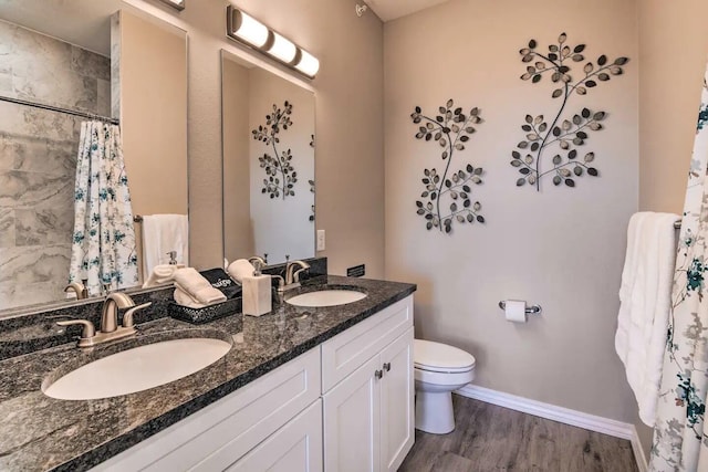 bathroom featuring curtained shower, wood-type flooring, vanity, and toilet