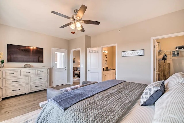 bedroom featuring light wood-type flooring, ceiling fan, a closet, a walk in closet, and ensuite bathroom