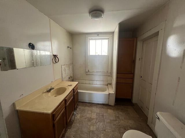 bathroom featuring vanity, a washtub, and toilet