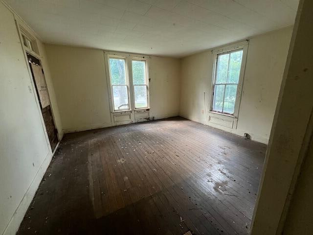 empty room with plenty of natural light and dark hardwood / wood-style flooring