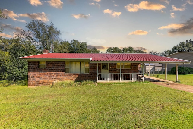 single story home featuring a yard, a carport, and covered porch