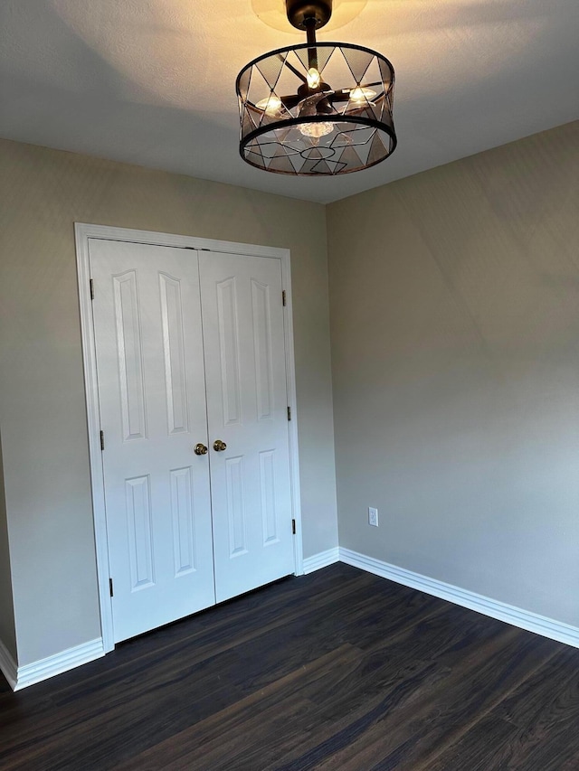 unfurnished bedroom with dark hardwood / wood-style flooring and a closet