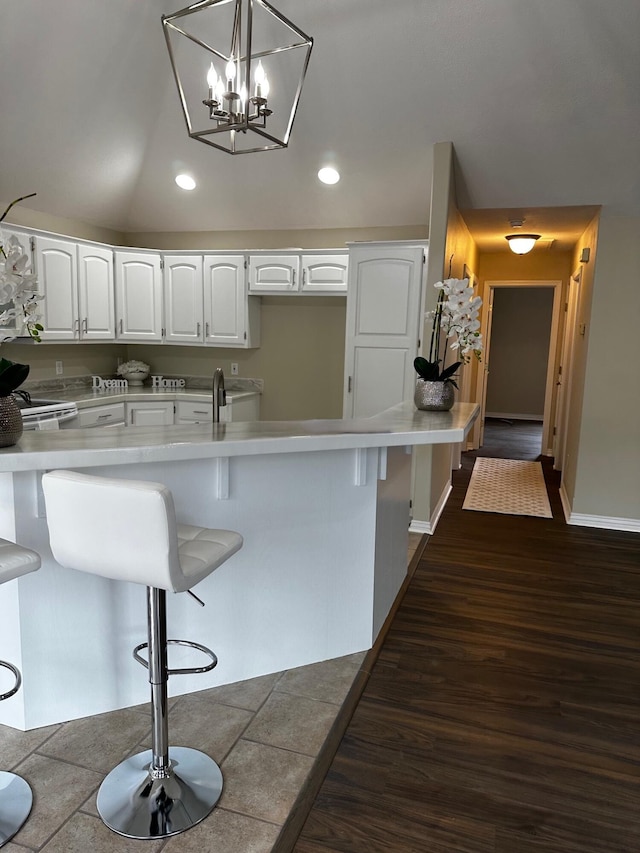 kitchen with white cabinets, hanging light fixtures, a breakfast bar area, and vaulted ceiling