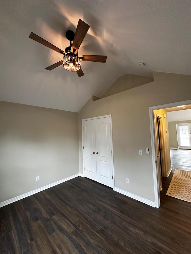 unfurnished bedroom featuring dark hardwood / wood-style flooring, a closet, ceiling fan, and lofted ceiling