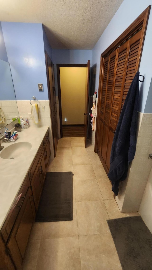 bathroom with tile patterned flooring, vanity, and a textured ceiling