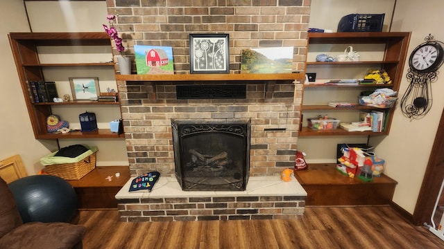 living room featuring a brick fireplace and dark hardwood / wood-style flooring