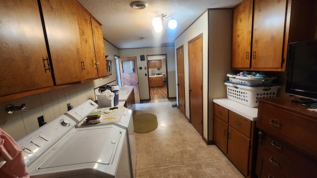 clothes washing area featuring cabinets, a textured ceiling, and independent washer and dryer