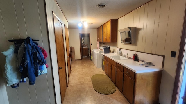 kitchen with wooden walls, sink, and a textured ceiling