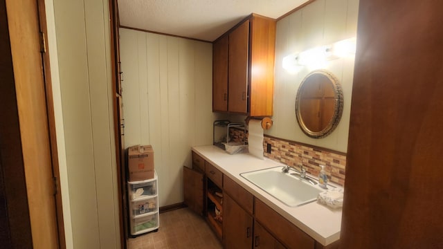 bathroom featuring decorative backsplash, wooden walls, vanity, and a textured ceiling