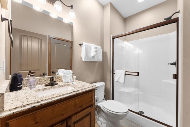 bathroom with a shower stall, toilet, and vanity