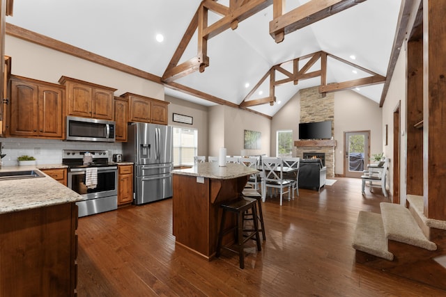 kitchen featuring a kitchen island, high vaulted ceiling, dark hardwood / wood-style floors, a breakfast bar area, and appliances with stainless steel finishes