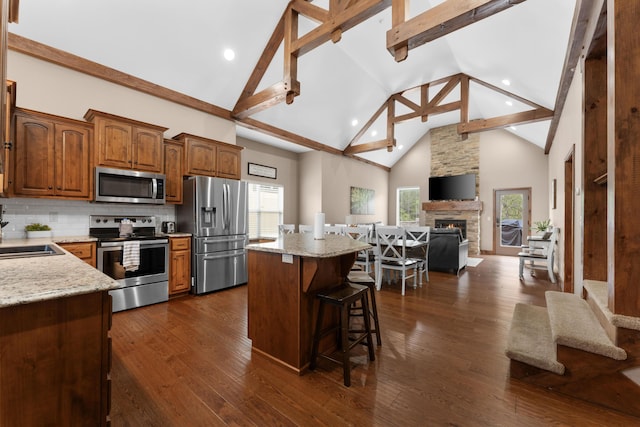 kitchen with stainless steel appliances, a kitchen bar, high vaulted ceiling, beamed ceiling, and a kitchen island