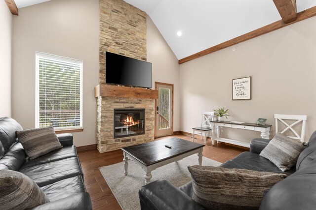 living room with dark wood-type flooring, high vaulted ceiling, and a stone fireplace