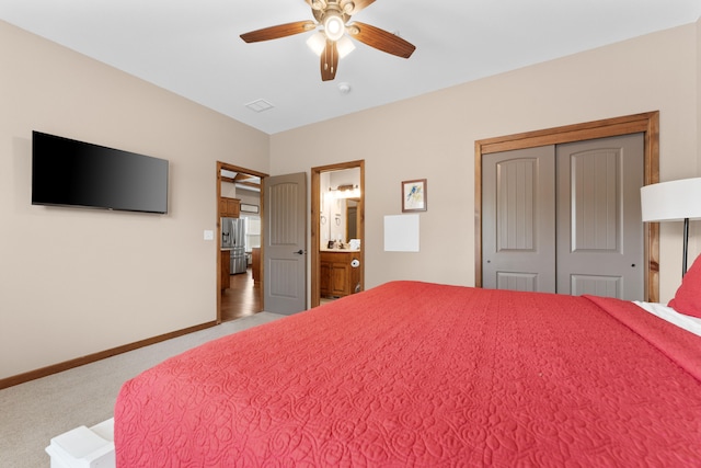 carpeted bedroom featuring ensuite bath, ceiling fan, and a closet