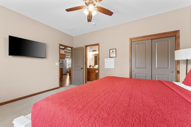 bedroom featuring a ceiling fan, ensuite bathroom, a closet, baseboards, and carpet flooring