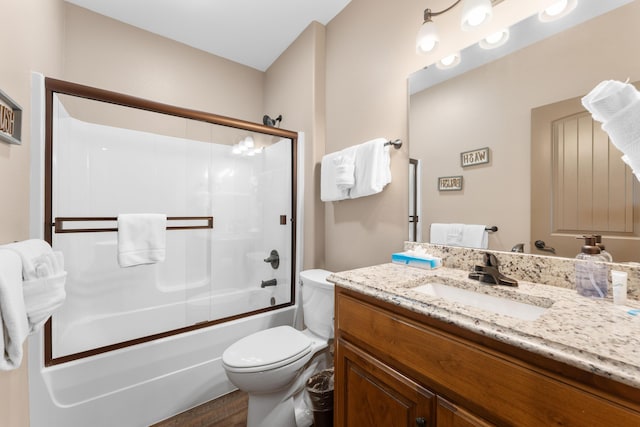 bathroom with wood finished floors, vanity, bath / shower combo with glass door, and toilet