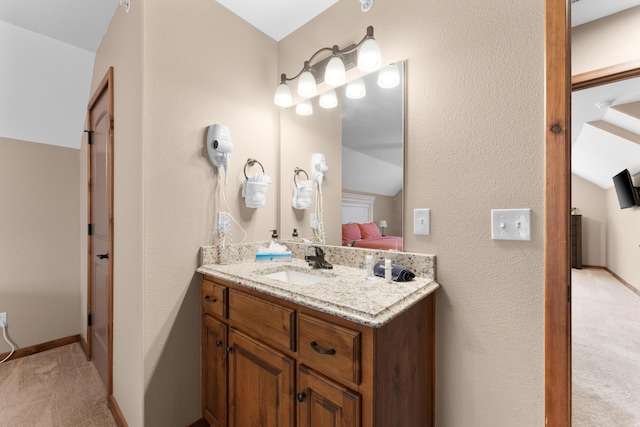bathroom with ensuite bath, a textured wall, and vanity